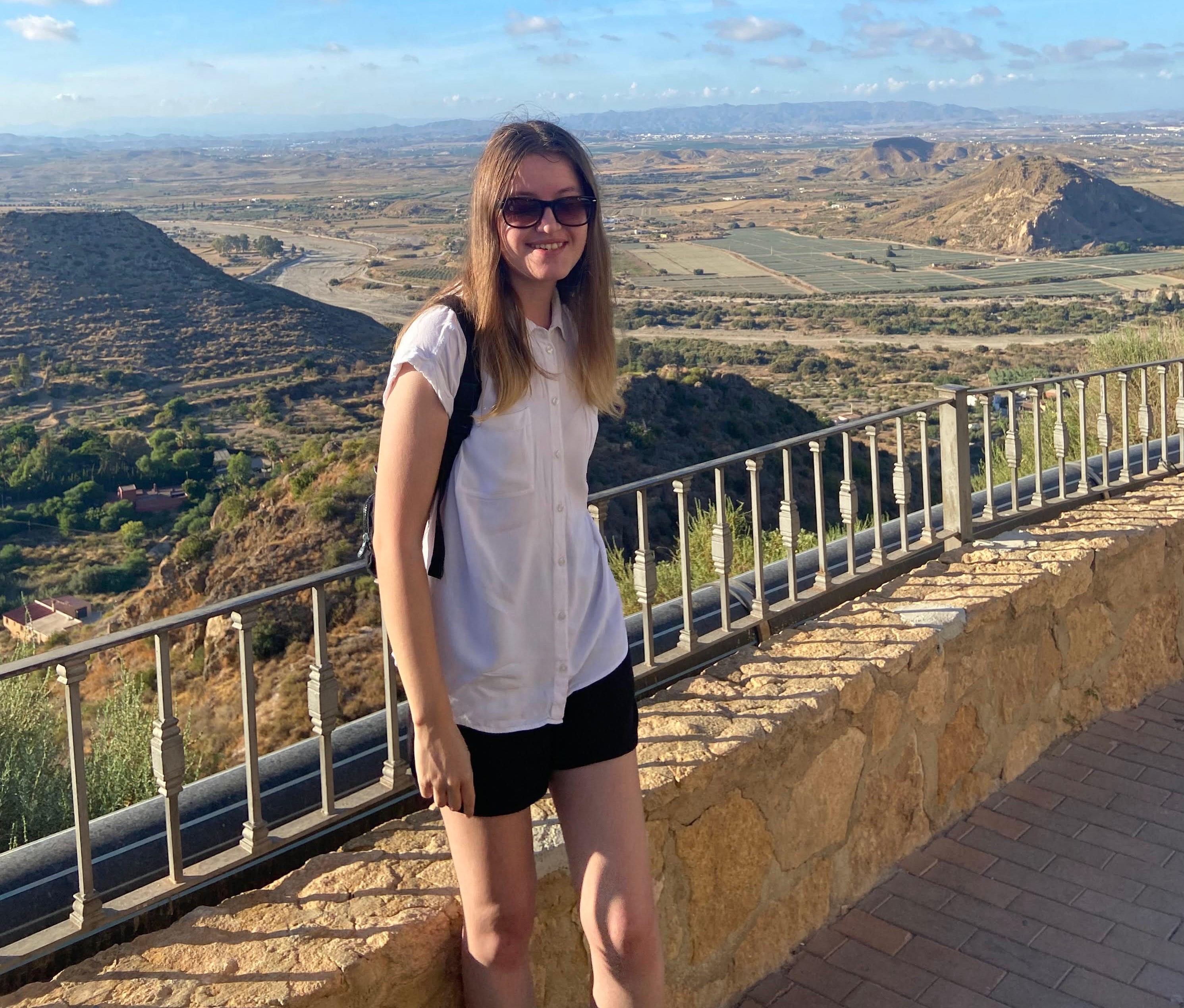 Profile picture of Charlotte Maynard - She is standing infront of a landscape in Mojacar, Spain.